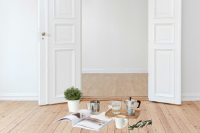 A white room with a book, coffee mugs and a potted plant