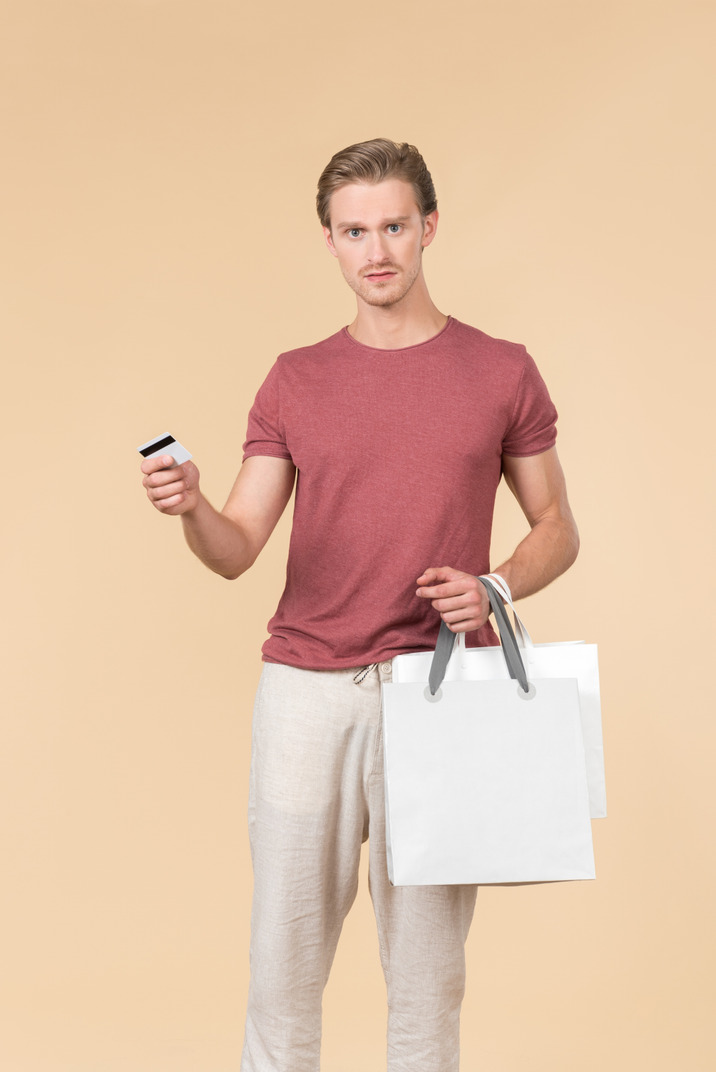 Young guy holding white shopping bags and a credit card