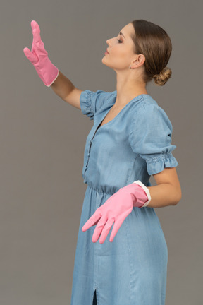 Beautiful young woman moving her arms while wearing cleaning gloves