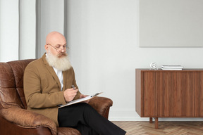 A man with a beard sitting in a leather chair