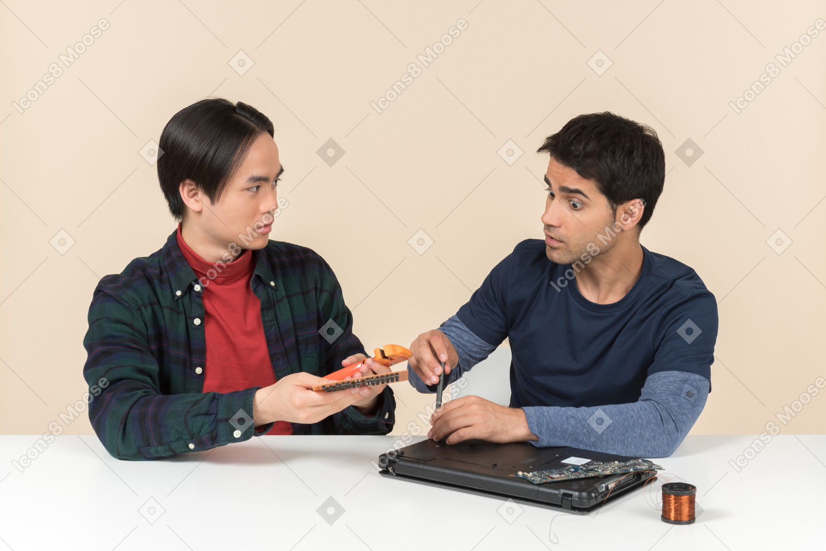 Due giovani geek seduti al tavolo e avendo problemi con la riparazione del laptop