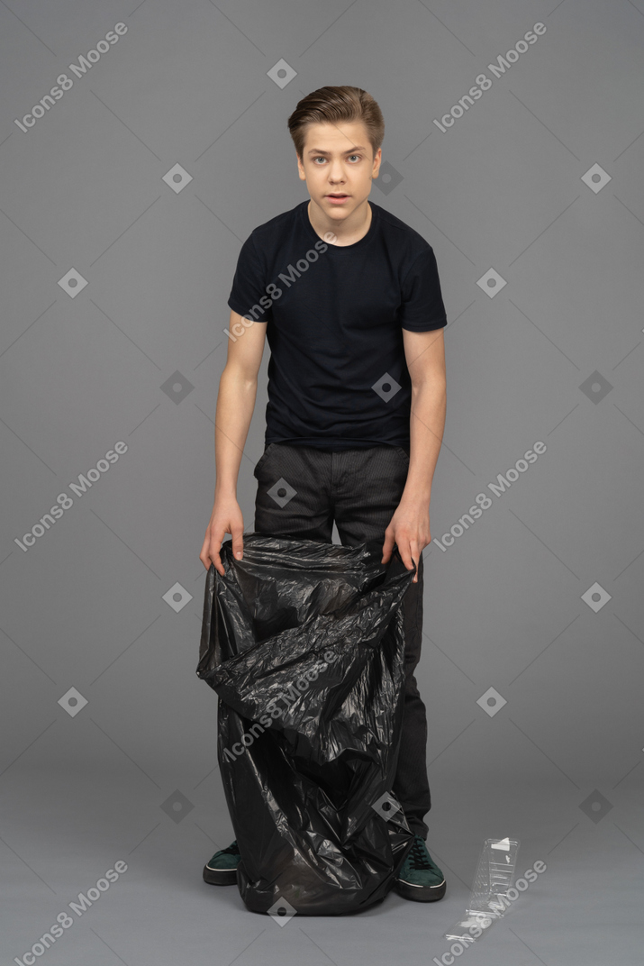 A man looking at camera with a trash bag in his hands