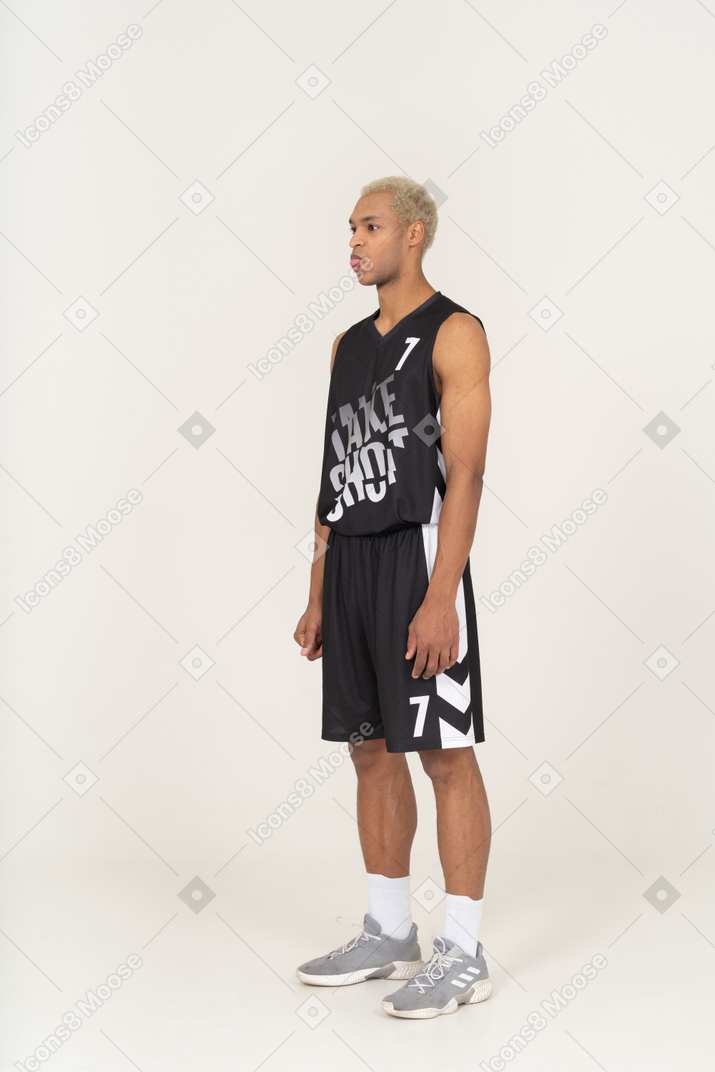 Vista di tre quarti di un giovane giocatore di basket maschile che mostra la lingua