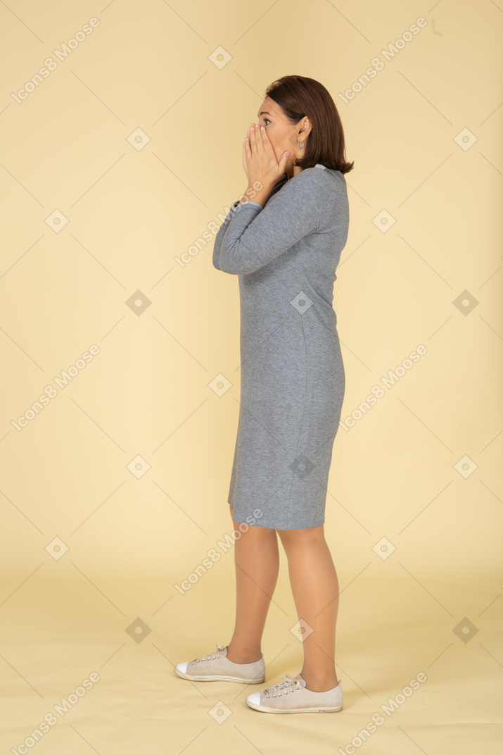 Impressed woman in grey dress standing in profile