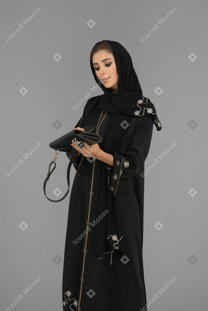 핸드백을 닫는 젊은 무슬림 여성