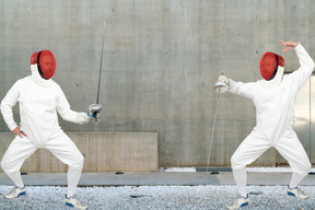 Men wearing fencing suits practicing with swords