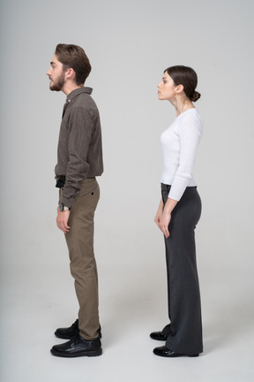 Vista lateral de um jovem casal com roupas de escritório levantando a cabeça