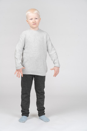 Фронтальный снимок недовольного маленького мальчика в повседневной одежде, жестикулирующего