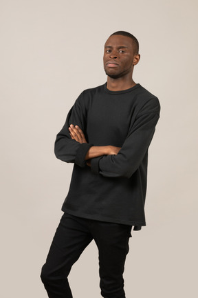 Three-quarter view of young man standing with arms crossed