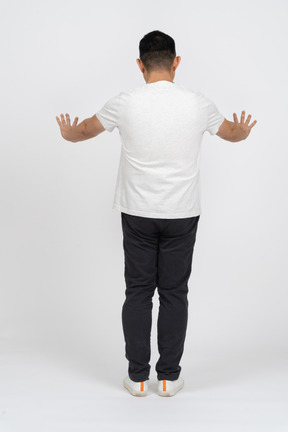 Vista traseira de um homem em roupas casuais em pé com os braços estendidos