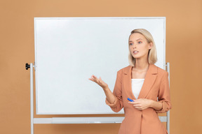 Mulher jovem e atraente explicando algo perto do quadro branco