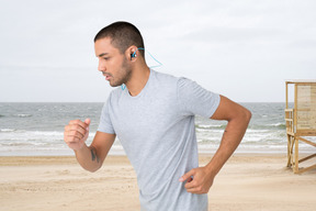 A man running on the beach with ear buds in his ears