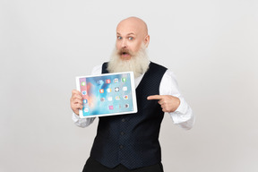 Excited mature man holding ipad and pointing on it