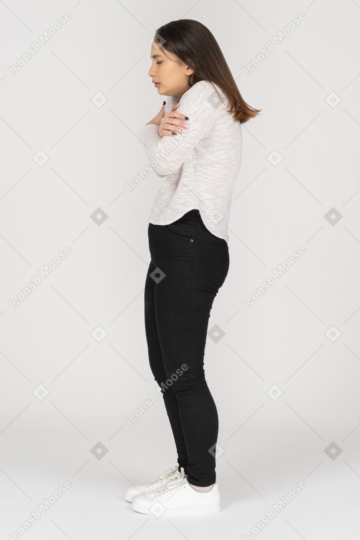 Side view of a frozen young indian female in casual clothing embracing herself