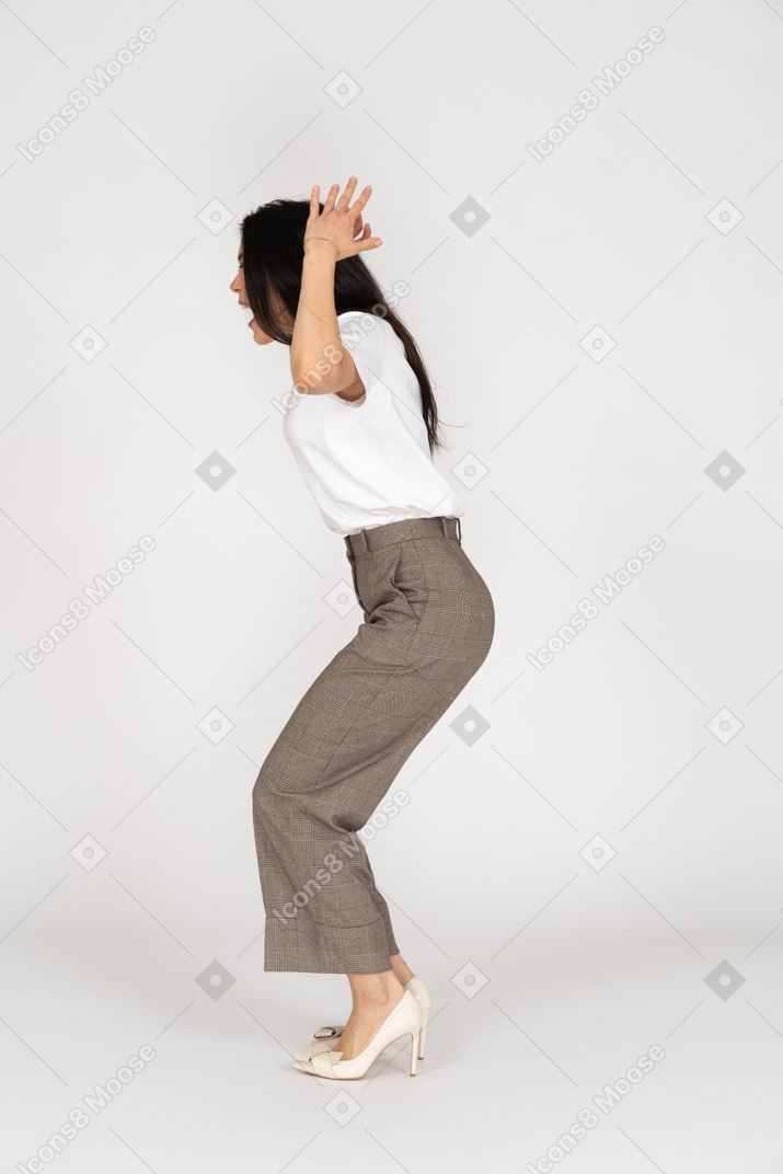 Side view of a shouting mad young lady in breeches and t-shirt raising her hands