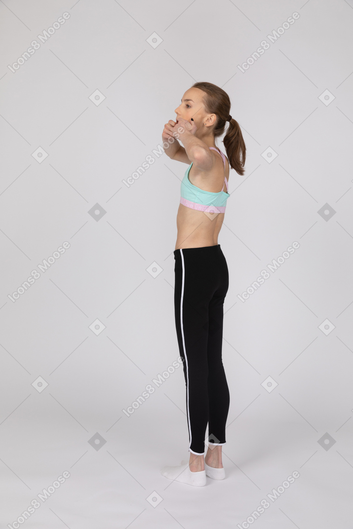 Vue latérale d'une adolescente en tenue de sport en levant la main et en faisant valoir