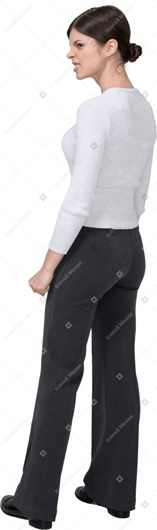 Vista posteriore di tre quarti di una donna furiosa in abiti da ufficio stringendo i pugni