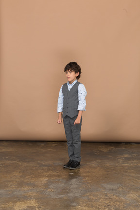 Vista frontal de un niño en traje gris parado