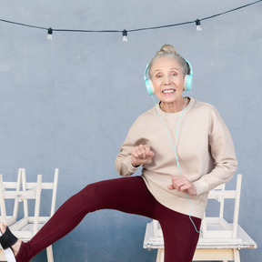 An older woman wearing headphones and dancing