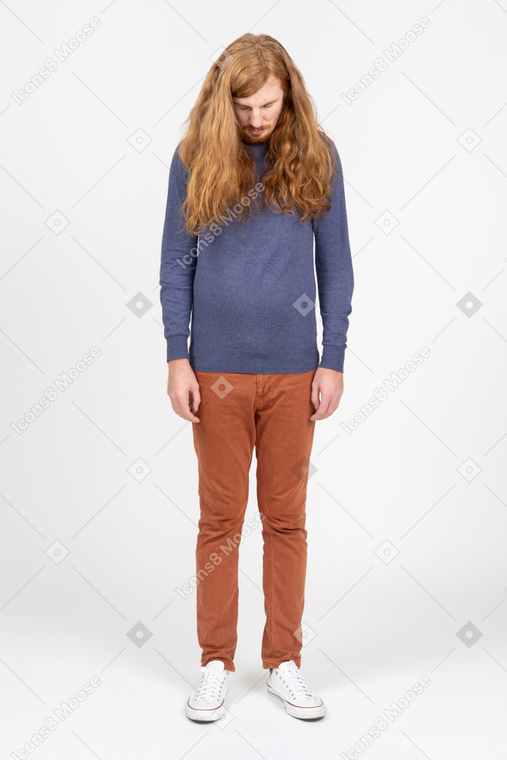 Young man in casual clothes looks down
