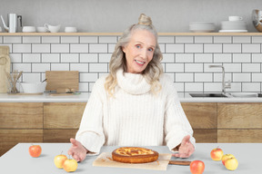 A woman standing in front of a cake on a cutting board