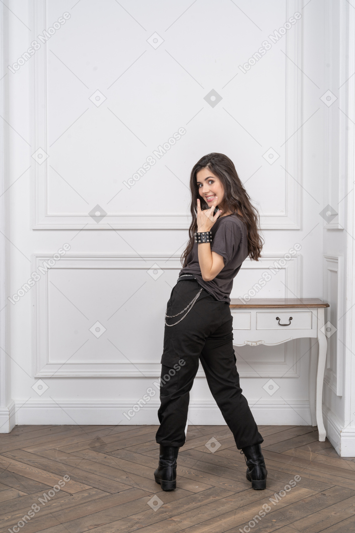 Vista posteriore di un rocker femminile che mostra un gesto rock