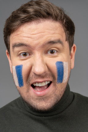 Un retrato de un fanático del fútbol masculino con arte de cara azul y blanca