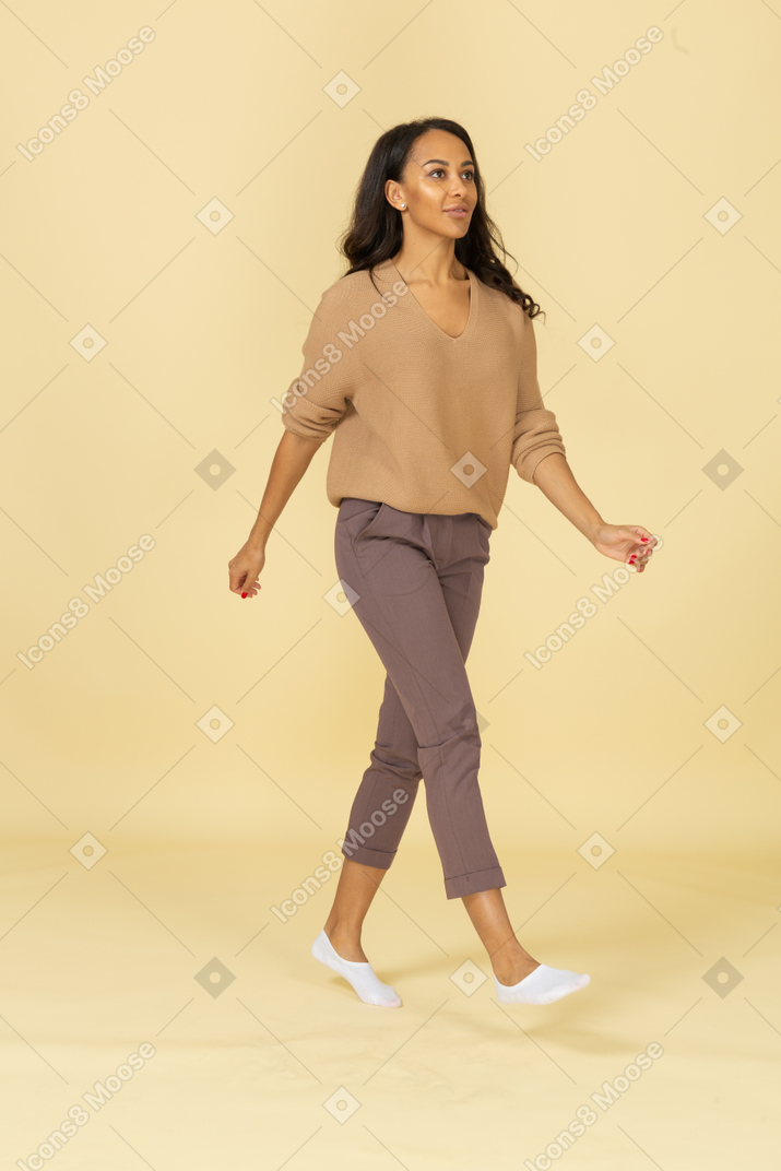 Vista de tres cuartos de una mujer joven caminando de piel oscura