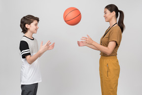 Pe insegnante femminile e allievo che pratica i servizi di pallacanestro