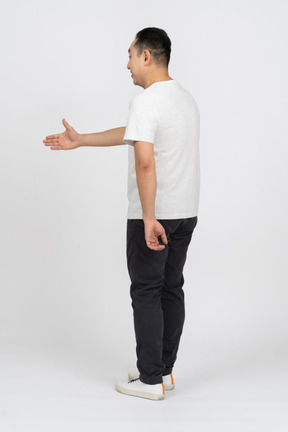 Вид в три четверти на человека в повседневной одежде, протягивающего руку для рукопожатия