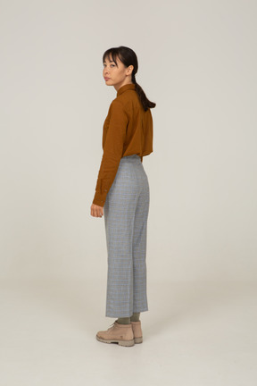 Three-quarter back view of a young asian female in breeches and blouse turning away
