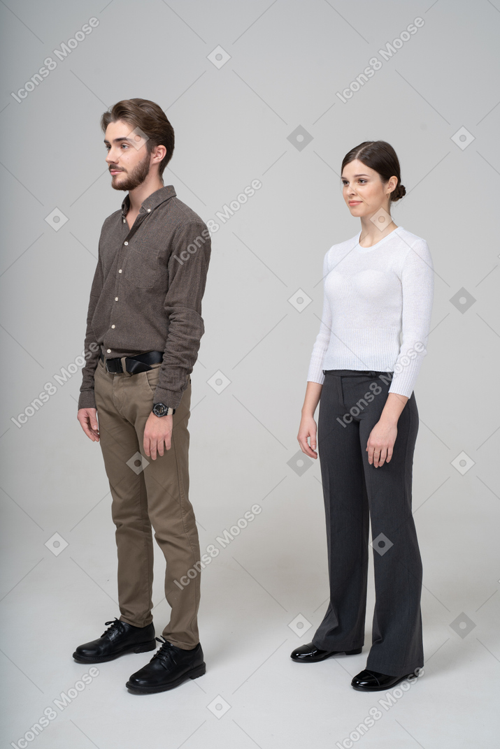 じっと立っているオフィス服の若いカップルの側面図