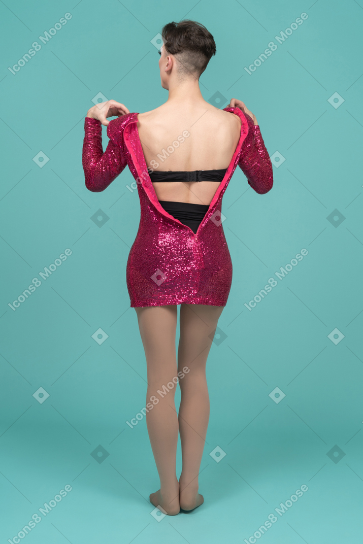 Vista traseira de uma drag queen tirando o vestido rosa