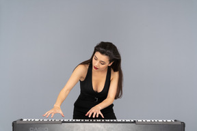 Vue de face d'une jeune femme en robe noire jouant du piano