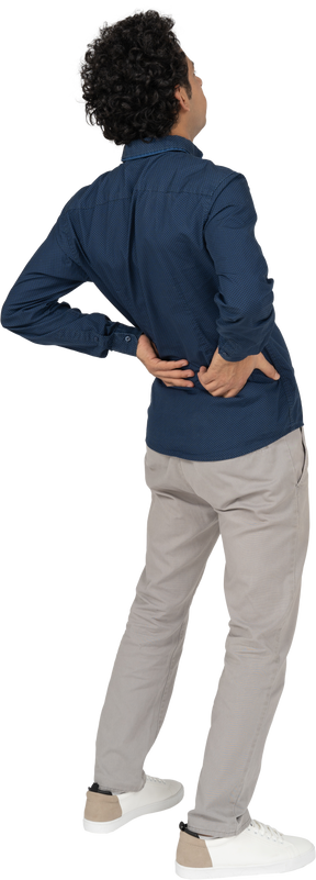 腰の痛みに苦しんでいるカジュアルな服装の男性の背面図