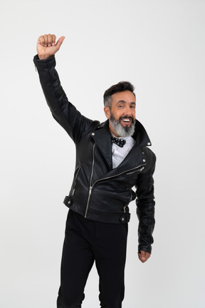Contented mature man wearing leathe jacket and holding his one hand up