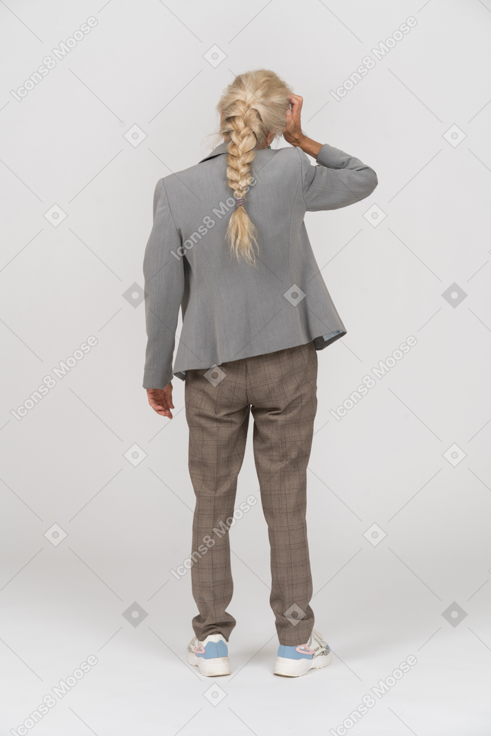 Back view of an old lady in suit suffering from headache