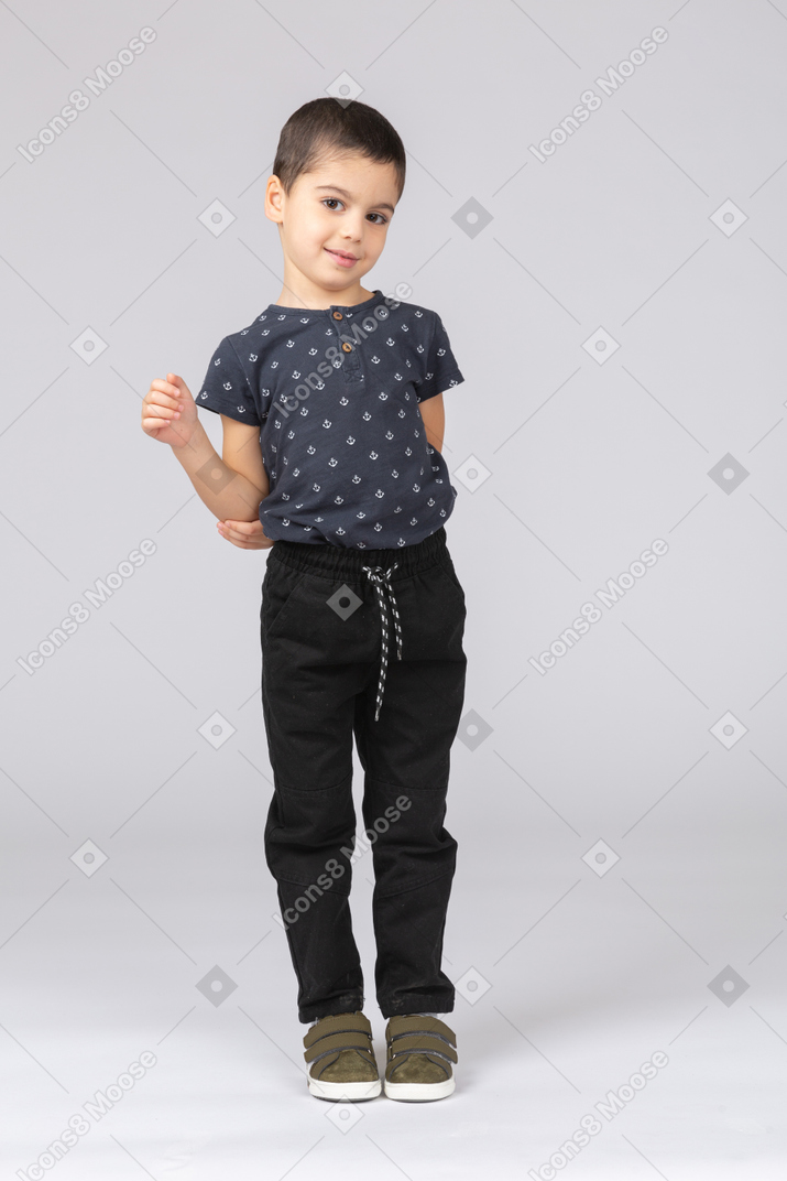 Vista frontal de um menino tímido em roupas casuais olhando para a câmera