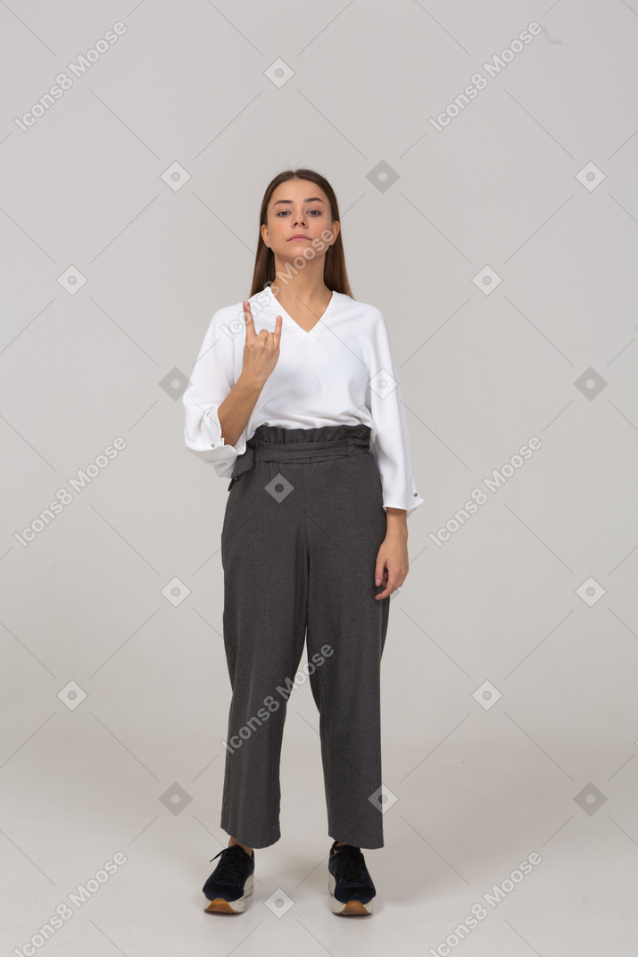 Front view of a young lady in office clothing showing rock gesture