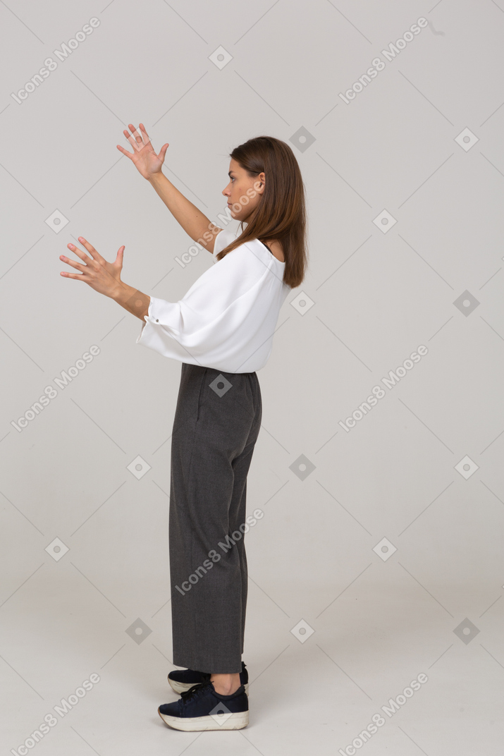 Vue latérale d'une jeune femme en vêtements de bureau montrant une taille de quelque chose