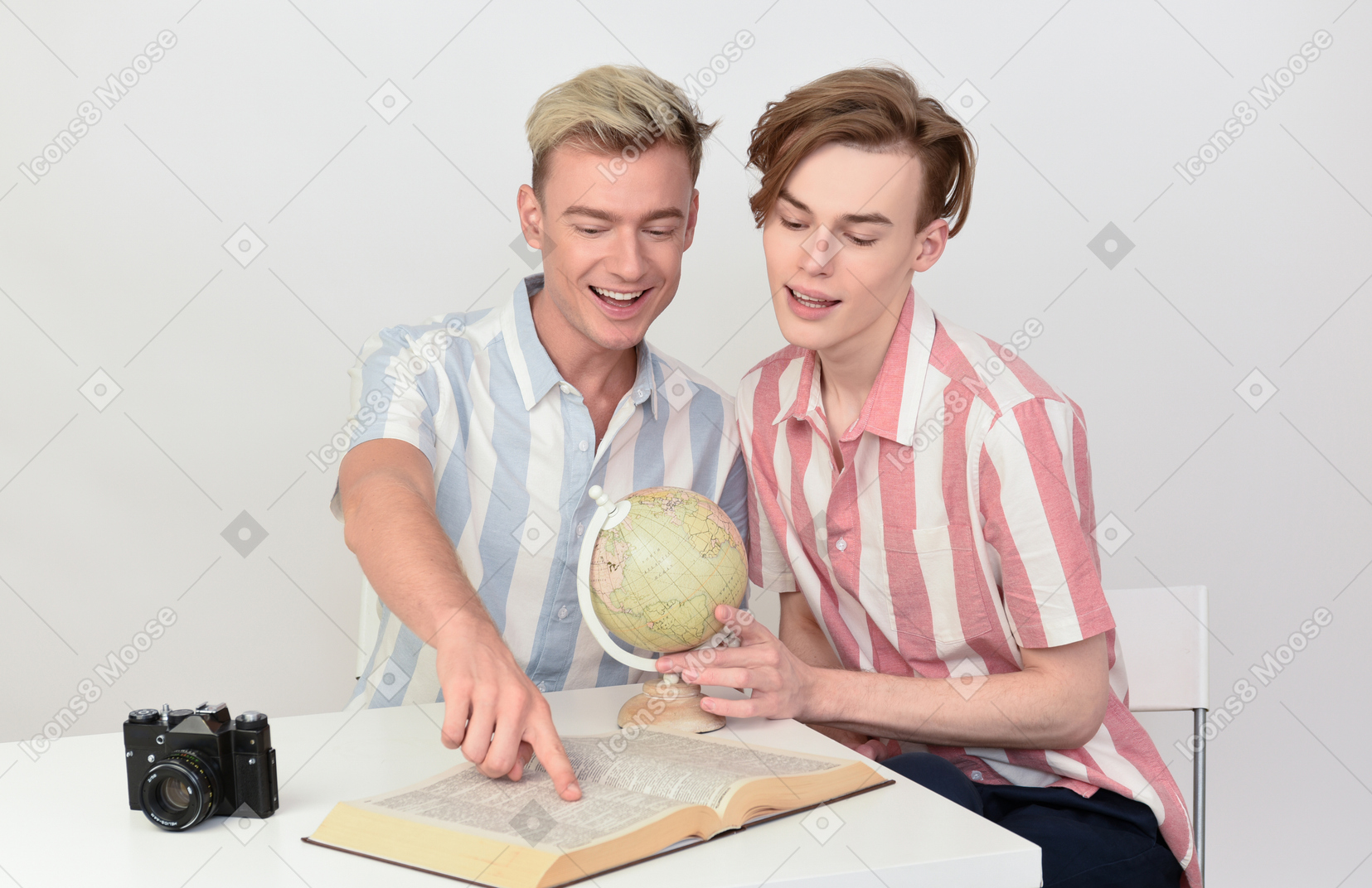 Gay couple reading book and holding a globe