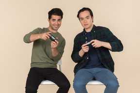 Interracial friends sitting in chairs and playing video games