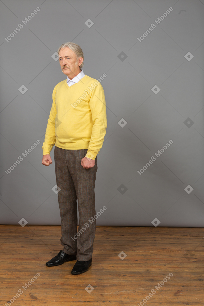 Three-quarter view of a depressed old man wearing a yellow pullover and looking aside