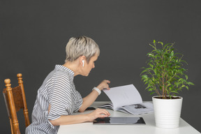 Femme à une table avec écouteurs, magazine et tablet pc