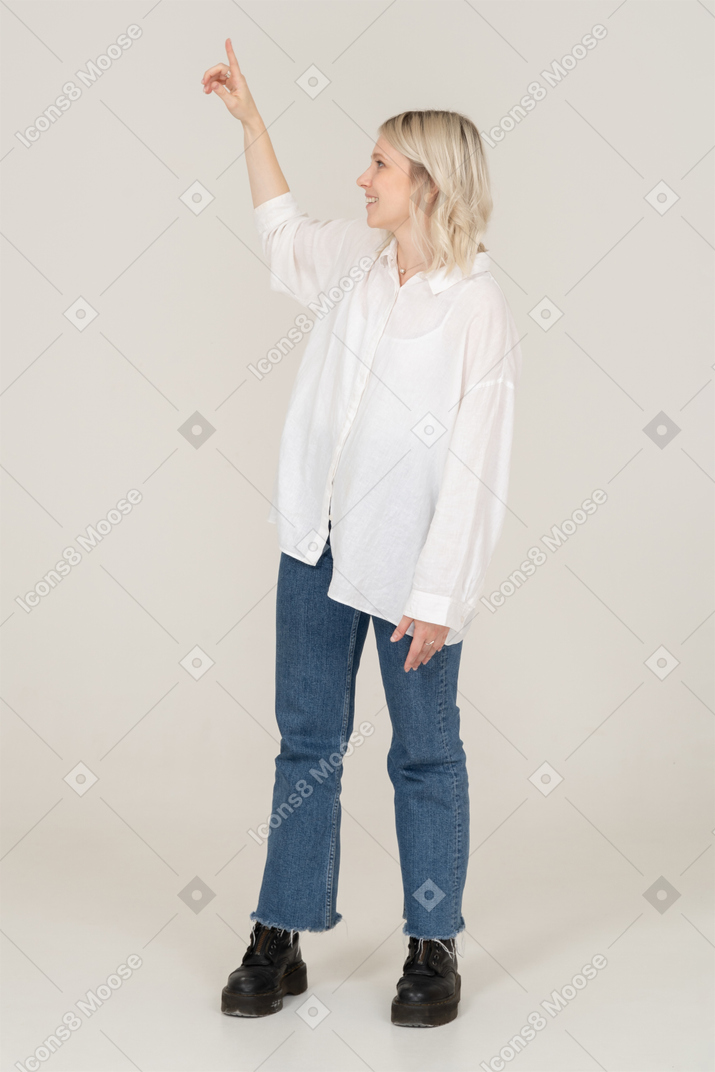 Vue de face d'une jeune femme blonde se détournant et pointant le doigt