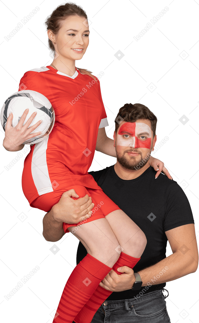 Front view of a male football fan holding in arms female soccer player
