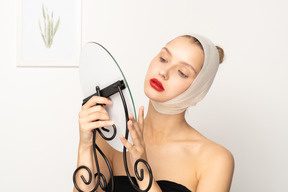 Mujer joven con vendaje en la cabeza sosteniendo un espejo