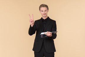 A white man in a fully black suit holding the quran