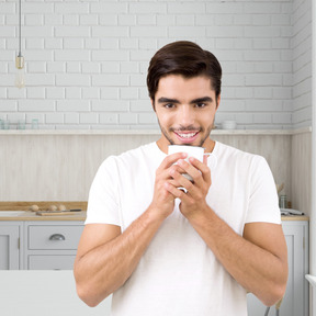 A man standing in a kitchen holding a cup