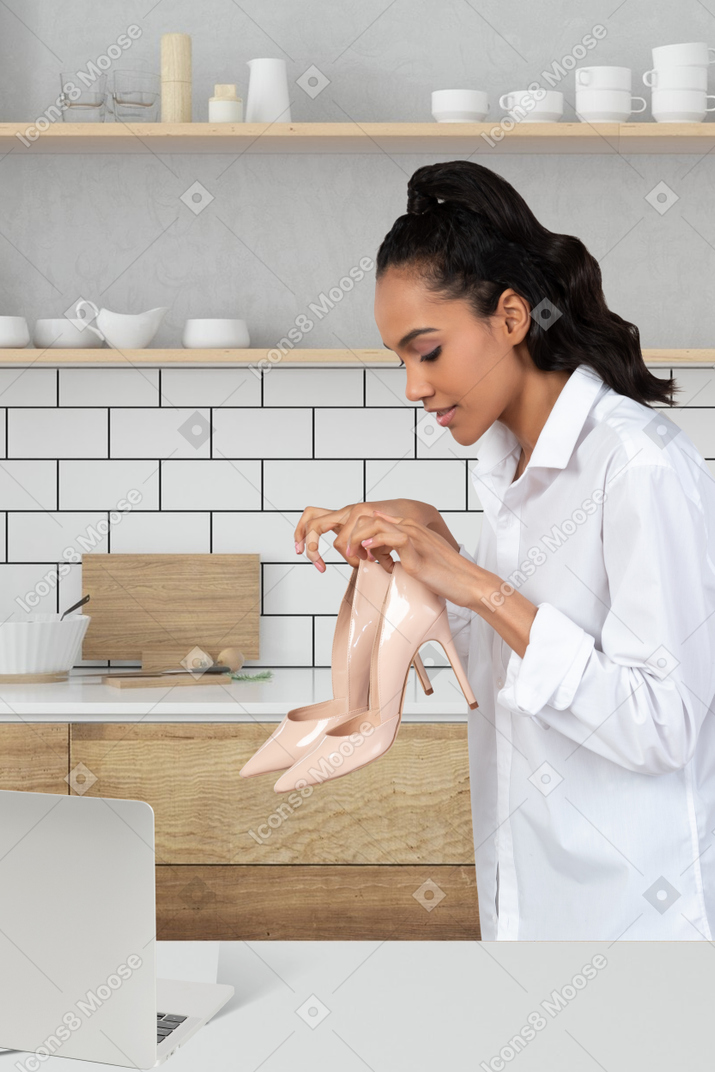 A woman in a white shirt is holding a pair of shoes
